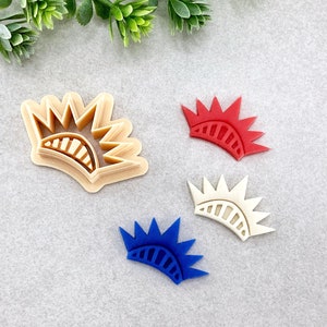 Può includere: Quattro stampini per biscotti a forma di corona con un design a stella. Gli stampini sono di colore rosso, bianco, blu e marrone.