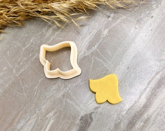 Peut inclure: Un emporte-pièce en plastique beige en forme de feuille, avec une feuille de fondant jaune à côté.