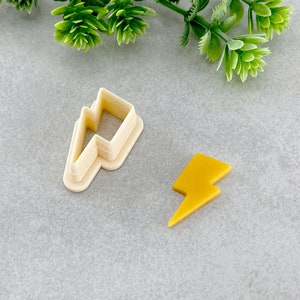 May include: Two lightning bolt cookie cutters, one is a white plastic cutter and the other is a yellow fondant cutout.