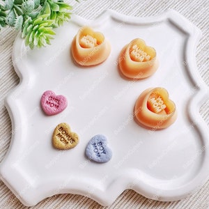 May include: Five heart-shaped candy molds with different messages: "Girl Mom", "Bonus Mom", "Boy Mom", "You Mom", and "Super Mom". The molds are made of a clear, flexible plastic and are perfect for making homemade candy.