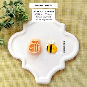 Pode incluir: Dois cortadores de biscoitos em forma de abelha, um em p&ecirc;ssego e outro em amarelo e preto, est&atilde;o em um prato decorativo branco. O texto "SINGLE CUTTER" e as op&ccedil;&otilde;es de tamanho s&atilde;o exibidos. Tamanhos dispon&iacute;veis: 19 mm, 25 mm e 32 mm.