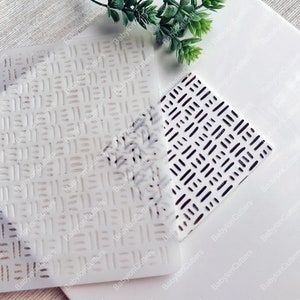 Op de afbeelding: Twee witte plastic sjablonen met geometrische patronen. De sjabloon links heeft een rasterpatroon met dunne lijnen. De sjabloon rechts heeft een patroon van korte, dikke lijnen.