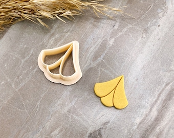 May include: Two plastic cookie cutters in the shape of a flower. The cutter on the left is white and the cutter on the right is yellow.
