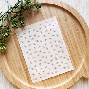 May include: A sheet of white paper with a repeating pattern of small brown bees. The bees are facing different directions and have a simple design.
