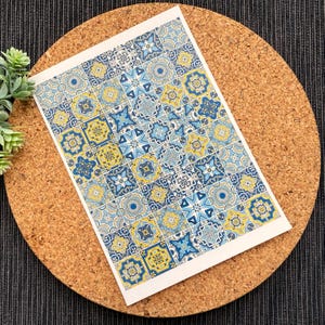 Può includere: Un foglio di carta decorativa con un motivo ripetitivo di piastrelle geometriche blu e gialle. Le piastrelle sono disposte a griglia e presentano una varietà di forme e disegni.