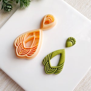 May include: Three polymer clay earring shapes, two are peach colored and one is green. The peach shapes are intricate and have a geometric design. The green shape is a teardrop with a geometric design.