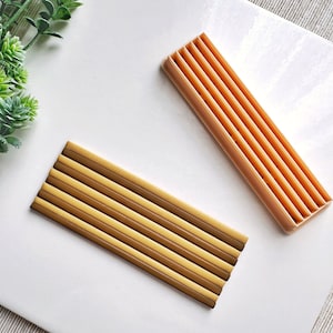 Può includere: Due porta bacchette in legno, uno è marrone chiaro e l'altro è marrone arancio scuro. Entrambi i porta bacchette hanno più fessure per le bacchette.