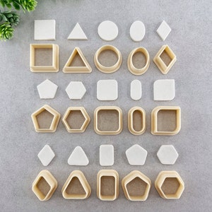 Peut inclure: Un ensemble de 24 emporte-pi&egrave;ces de diff&eacute;rentes formes, notamment des cercles, des carr&eacute;s, des triangles, des losanges, des &eacute;toiles et des hexagones. Les emporte-pi&egrave;ces sont en plastique brun clair et sont dispos&eacute;s en rang&eacute;es sur une surface grise.