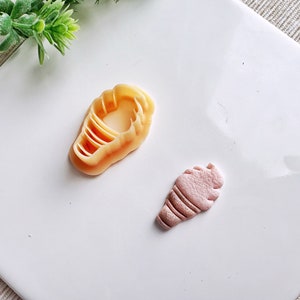 Può includere: Due stampi in silicone per fare coni gelato. Uno stampo è di colore marrone chiaro e ha la forma di un cono waffle. L'altro stampo è di colore rosa chiaro e ha la forma di un cono gelato ripieno.