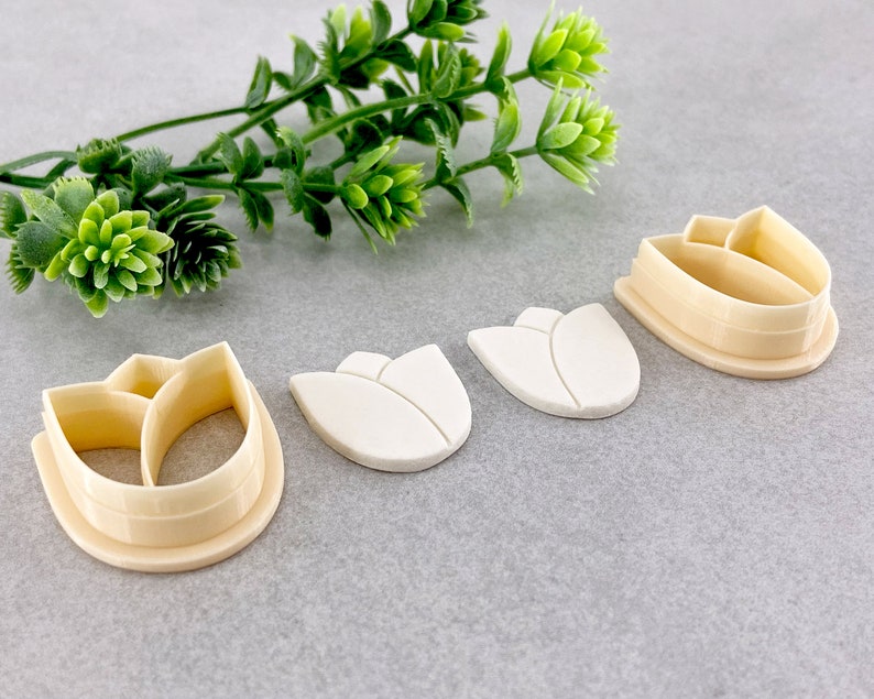 May include: Three white plastic tulip-shaped cookie cutters and one beige plastic tulip-shaped cookie cutter with a detailed design.