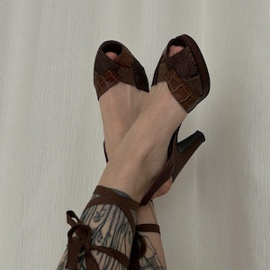 Op de afbeelding: Bruine leren sandalen met hak, peeptoe en enkelbandjes. De sandalen zijn gemaakt van verschillende stukken leer, waaronder krokodillenleer.