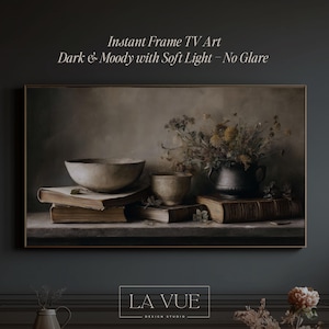 May include: A framed digital art print featuring a still life with a bowl, cup, and vase of flowers on books. The artwork has a dark, moody aesthetic with soft lighting. The text on the image reads "Instant Frame TV Art" and "Dark & Moody with Soft Light - No Glare."