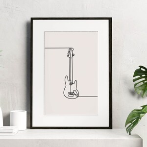 May include: A black framed print with a white background featuring a line drawing of a bass guitar.