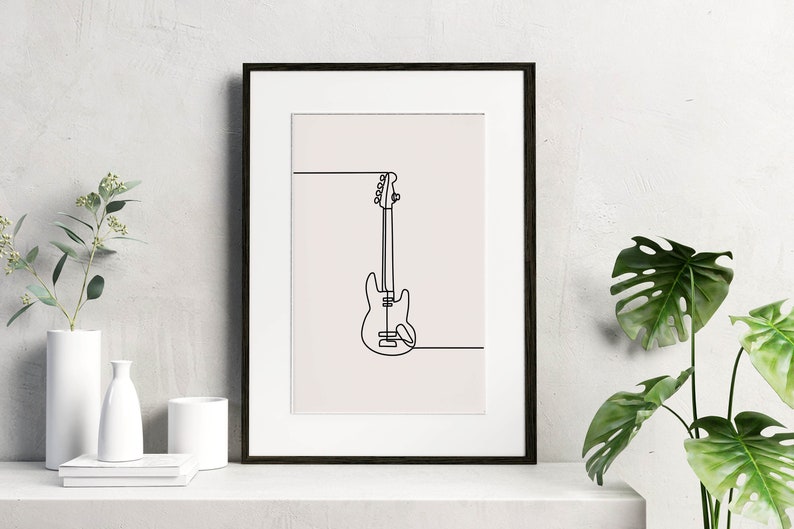 May include: A black framed print with a white background featuring a line drawing of a bass guitar.