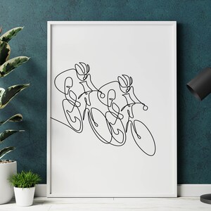 May include: A black and white line drawing of two cyclists racing on bicycles. The drawing is framed in a white frame and is hanging on a teal wall.