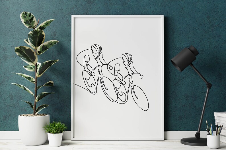 May include: A black and white line drawing of two cyclists racing on bicycles. The drawing is framed in a white frame and is hanging on a teal wall.