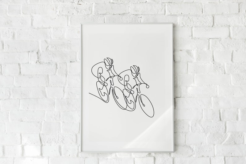 May include: A black and white line drawing of two cyclists racing on bicycles. The drawing is framed and hanging on a white brick wall.