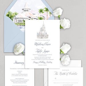 May include: A wedding invitation suite featuring a light blue envelope with a watercolor illustration of a resort, a main card with a castle illustration, an itinerary card, and a response card, all accented with white flowers.