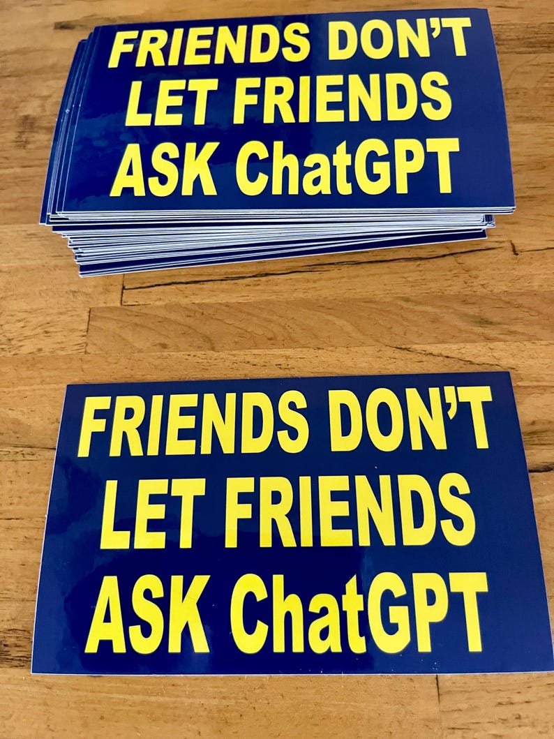 May include: A stack of blue rectangular stickers with yellow text that reads "FRIENDS DON'T LET FRIENDS ASK ChatGPT". The stickers are on a wooden surface.