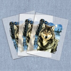 May include: A gray wolf with brown fur stands in a snowy forest with a full moon in the background. The wolf is looking directly at the viewer.
