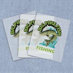 May include: Three light gray t-shirts with a graphic of a pike fish jumping out of the water. The text "BIG PIKE FISH" is arched above the fish in green, with "FISHING" below. "Catch and Release" is below the word "FISHING".