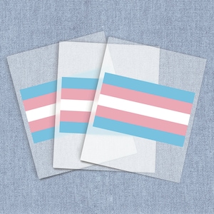 May include: Three translucent sheets of paper with a transgender pride flag printed on them. The flag is light blue, pink, and white with horizontal stripes.