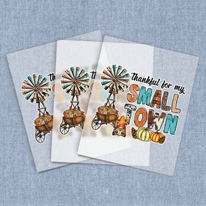 May include: Three white iron-on transfer sheets with a design of a windmill, a wagon full of pumpkins, a gnome, and the text "thankful for my SMALL TOWN".