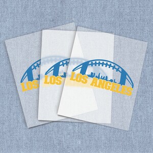 May include: Four white sheets of paper with a blue and yellow graphic of a football and the text "Los Angeles" printed on them.