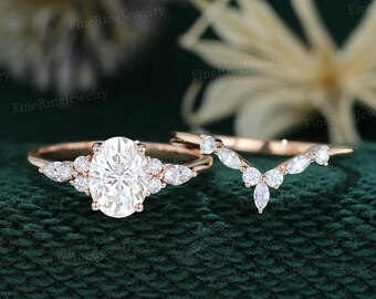 May include: A rose gold engagement ring set with an oval-shaped center stone and a matching contoured wedding band. Both rings feature a delicate pear-shaped diamond accents.