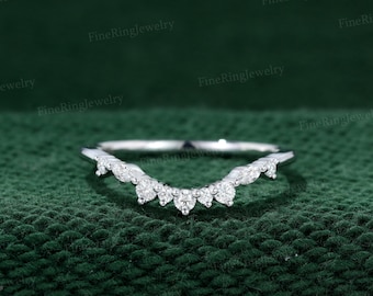 May include: A delicate, curved wedding band with a row of small, sparkling diamonds set in a white metal band.