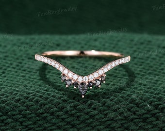 May include: A delicate, curved wedding band with a V-shaped design. The band is set with small, sparkling diamonds and black diamonds, creating a unique and elegant look.
