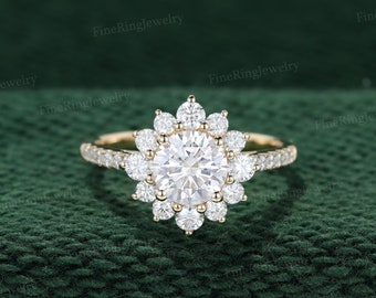 May include: A gold engagement ring with a large round center diamond surrounded by a halo of smaller diamonds. The ring band is also set with smaller diamonds.