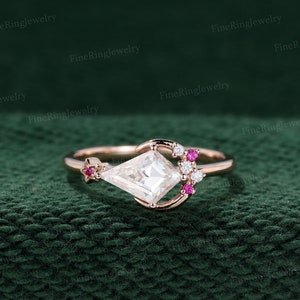 May include: A rose gold engagement ring featuring a crescent moon design and a square-shaped diamond. The ring is set with small diamonds and pink gemstones.