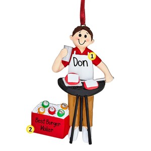 May include: A red and white personalized ornament of a person grilling burgers. The ornament features a grill, a cooler with the text "Best Burger Maker", and the name "Don".