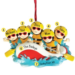 Puede incluir: Adorno de una familia de cinco en una balsa blanca y roja, con cascos y chalecos salvavidas amarillos. El adorno tiene el texto "The Baileys" y "Gauley River, WV".
