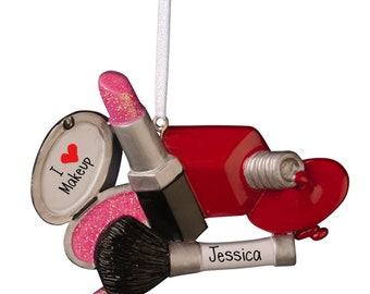 May include: A personalized Christmas ornament featuring a makeup set with a red nail polish bottle, a pink blush compact, a black makeup brush, and a red lipstick. The ornament is decorated with glitter and the text "I love makeup" and "Jessica".