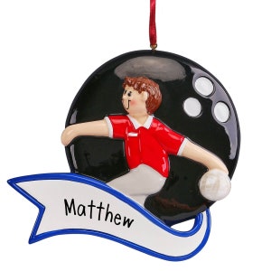 May include: A black and white bowling ball ornament with a cartoon figure of a person bowling. The ornament has a blue banner with the name "Matthew" written in white.