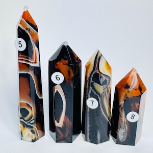 May include: Four polished stone towers arranged in a row, labeled with white circular stickers numbered 5, 6, 7, and 8. Each tower features a banded pattern of deep black, translucent amber, and white mineral layers with a smooth, faceted finish.