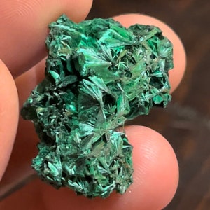 Op de afbeelding: Een cluster van groene malachietkristallen met een ruw, getextureerd oppervlak.