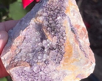 May include: A cluster of purple amethyst crystals in a rough, natural formation. The crystals are clustered together in a dense, almost solid mass, with a few larger crystals protruding from the surface. The amethyst is a deep purple color, with a slight sheen.