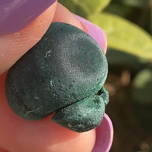 Op de afbeelding: Een donkergroene malachiet steen met een glad, afgerond oppervlak. De steen heeft een natuurlijke, organische vorm en een licht getextureerde afwerking.