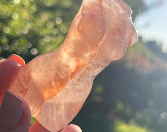 May include: A carved pink and orange crystal sculpture of a human torso.