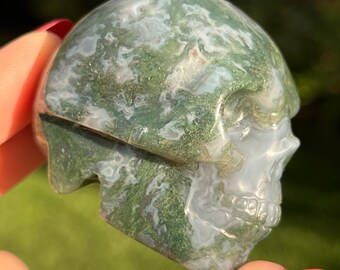 May include: Green and white agate skull carving. The skull is polished and has a smooth, glossy finish.