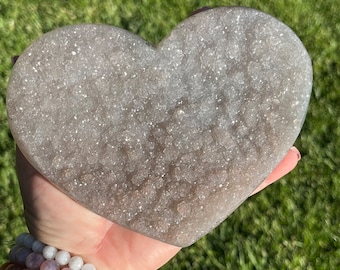 May include: A large, heart-shaped amethyst crystal with a light purple hue and a sparkly, textured surface.