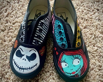 May include: A pair of black canvas shoes with hand-painted designs of Jack Skellington and Sally from the Nightmare Before Christmas movie. The shoes have white stripes and polka dots.