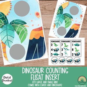 May include: A digital download of a dinosaur-themed counting insert for a Flisat bin. The insert features a watercolor design with a volcano, palm trees, and a blue sky. Includes cards with dinosaur illustrations and numbers.