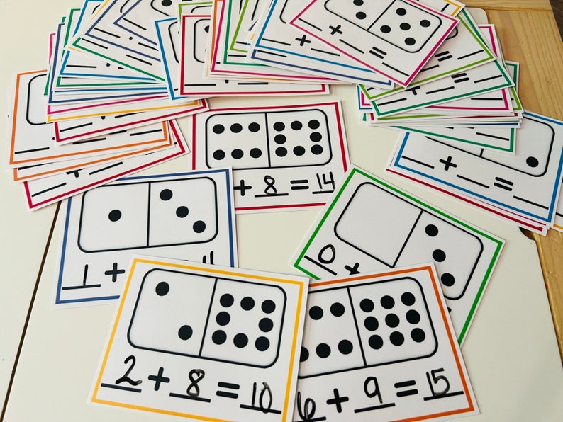 May include: A set of colourful printable domino cards with black dots and addition equations. The cards feature dominoes with different numbers of dots and corresponding addition problems, such as 2 + 8 = 10 and 6 + 9 = 15.