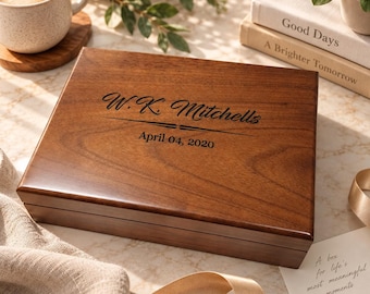 May include: A rectangular wooden box with a smooth, polished finish. The lid is engraved with the text W.K. Mitchells and the date April 04, 2020, separated by a decorative horizontal line. The box features a rich, dark brown wood grain.