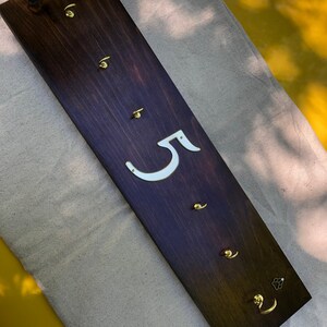 Può includere: Un porta chiavi in legno marrone scuro con cinque ganci in ottone e il numero "5" bianco sul davanti.
