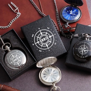 a collection of three pocket watches, each with a unique design and color, displayed on a dark surface.
